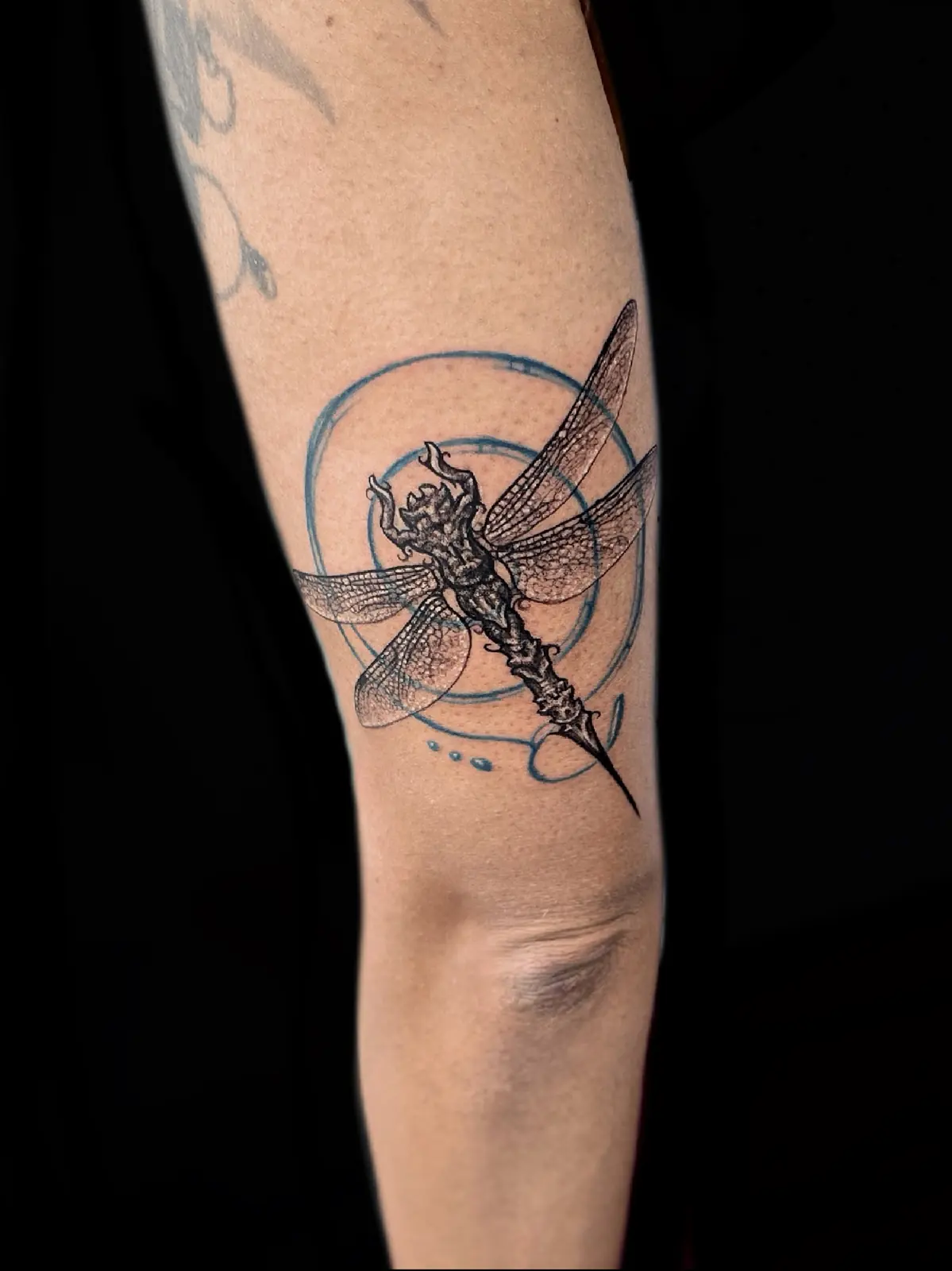 Dragonfly inside a fine-line circle on a forearm